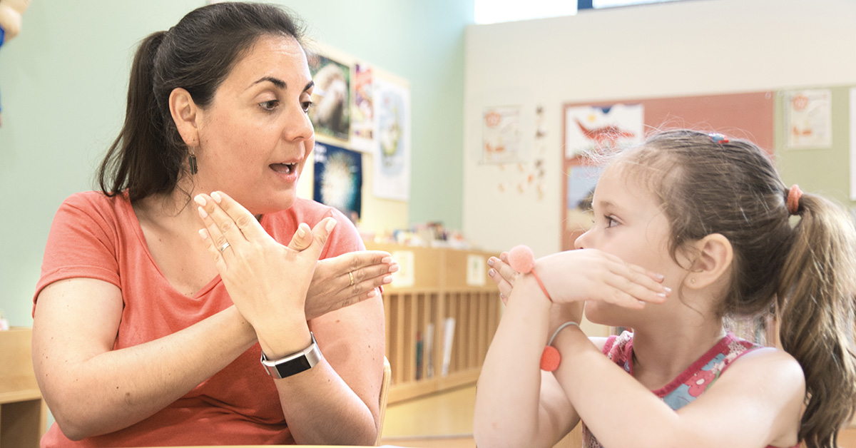 Sign language teacher in a tutoring class with a deaf child girl using sign language