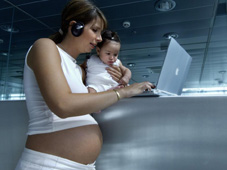 Pregnant woman with baby working on a computer